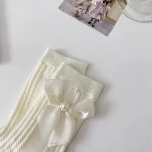 Détail de chaussettes nœud Lolita mi-mollet, vue rapprochée chaussettes perles tricot.