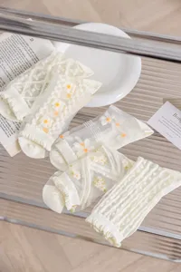 Nahaufnahme von transparenten weißen Blumen-Kristallsocken mit feinem Netz und Stickerei.