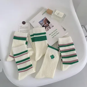 Close-up detail of white mid-tube socks featuring classic green and pink stripes design.