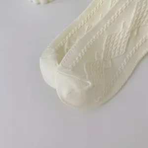 Fine detail view of women's knitted cotton socks featuring delicate cable knit patterns.