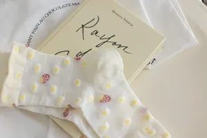 Close-up detail of white women mid-calf socks featuring sweet strawberry and cute daisy patterns.