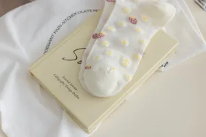 White cotton mid-tube socks with strawberry and daisy prints, sweet Japanese style daily wear detail.