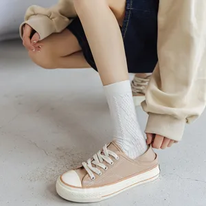 Women's white knit mid-tube socks with textured pattern worn with casual canvas shoes.