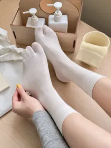 Close-up detail of white split-toe socks made of thin silk, showing toe and fine fabric texture.