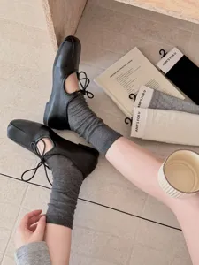 Damen lässige graue Stinosocken kombiniert mit schwarzen Mary Jane Schuhen im Detail.