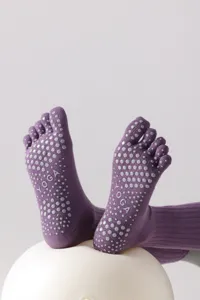 Close-up detail of purple five-toe yoga socks with non-slip silicone grip dots for pilates.