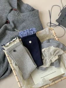 Detail shot of women's mid-calf socks with cute ruffles and buttons in a cozy basket.