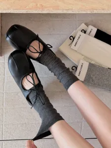 Detailaufnahme von einfarbigen Stegstrümpfen und schwarzen Schuhen mit quadratischer Kappe.