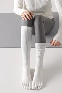 Detailed view of women white five toe yoga socks knee high pilates socks.