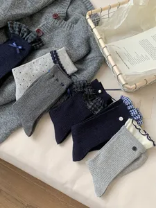 Detailed view of blue grey mid calf socks featuring delicate lace ruffles and cute button accents.