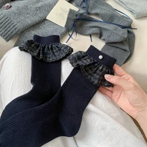 Close-up detail of dark blue mid-calf socks featuring stylish plaid ruffles and pearls.