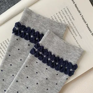 Grey mid-tube socks detail view showcasing navy blue textured ruffles and cute polka dots pattern
