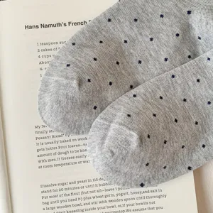 Close-up detail of gray breathable knit mid-calf socks with delicate dark blue clover patterns.