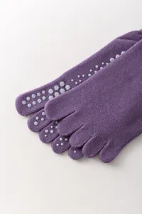 Detailed view of purple five toe yoga socks with anti slip grip dots on sole and toes.