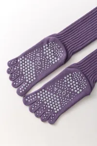 Close-up detail of purple five-toe yoga socks with anti-slip grip dots on the sole.