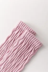 Dettaglio di calze slouch a costine in maglia rosa, consistenza morbida e vestibilità comoda.