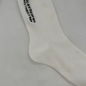 Primo piano dettagliato di calzini bianchi in cotone a costine con elegante ricamo di lettere.