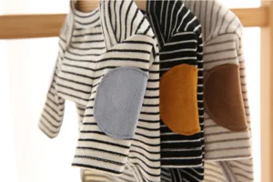 Detailed close-up of cute striped pet dog sweatshirt with colorful elbow patches hanging.