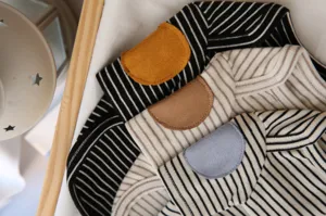Close-up detail showing the soft striped fabric and decorative shoulder patch of the pet sweater.