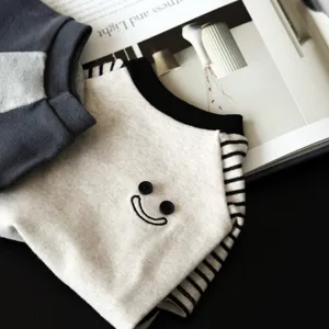 Detailed shot of pet sweatshirt with striped sleeves and cute button embroidery design.