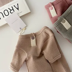 Detail view of soft waffle knit pet sweater in neutral and pastel tones, flat lay display.