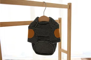 Closeup of a cute black and white striped pet sweater with yellow elbow patches on a hanger.