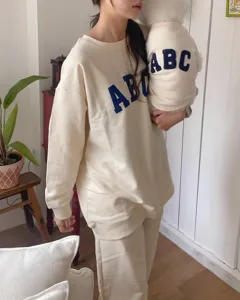 Detailed view of beige pet sweatshirt with bold ABC embroidery, cozy lifestyle dog apparel shot.