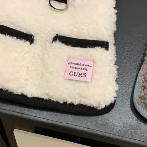Vue détaillée du gilet pour animal en sherpa blanc avec bordure noire et étiquette.