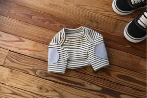 Detail shot of pet striped sweatshirt with blue elbow patches on wood background.