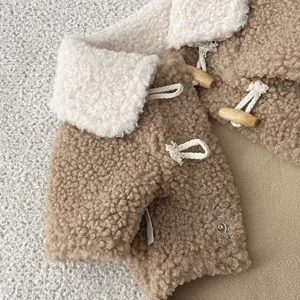 Gros plan sur le manteau polaire douillet pour animaux avec col blanc et boutons en bois.