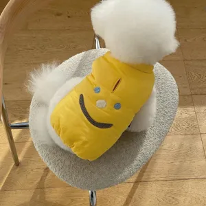 Detail view of a cute pet winter warm cotton coat in bright yellow with lovely smiley embroidery.