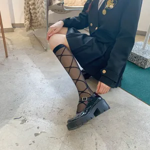 Close-up detail of sheer black calf socks featuring trendy argyle pattern, perfect for summer.