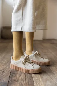 Detail shot of warm thick mustard yellow towel socks paired with beige platform sneakers.