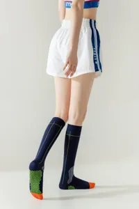 Detail shot of dark blue functional knee-high athletic socks with grip soles and green lines.