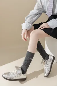 Chaussettes hautes grises côtelées pour femmes avec broderie d'abeille et baskets argentées.