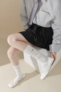 Chaussettes hautes côtelées blanches avec broderie d'abeille délicate pour look élégant.