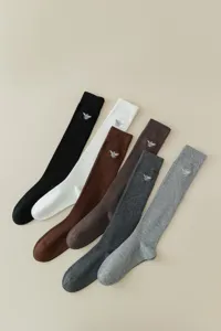 Gros plan de chaussettes hautes côtelées de différentes couleurs avec motif d'abeille brodé.
