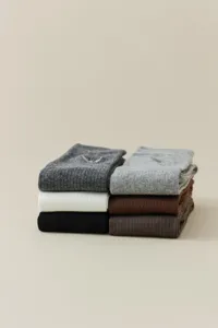 Vue détaillée de chaussettes en tricot côtelé empilées aux couleurs neutres et douces.