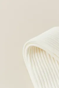 Detailed close-up shot of cream white ribbed knit fabric texture, fine craftsmanship