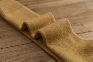 Detailed close-up of thick winter warm loop knit long socks in solid mustard yellow color.