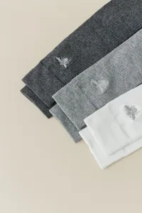 Détail en gros plan de chaussettes hautes côturées avec broderie d'abeille délicate en plusieurs.