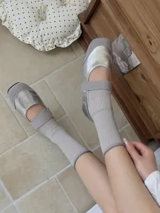 Women summer thin mid-tube solid color socks paired with stylish metallic silver flat shoes.