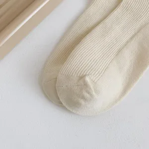 Gros plan sur des chaussettes beiges côtelées, texture tricotée douce pour un style cozy.