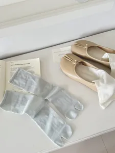 Close-up view of light blue split-toe socks on a clean surface with lifestyle props.
