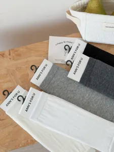 Detailansicht einfarbiger kurzer Baumwollsocken in Weiß, Grau und Schwarz mit Anhängern.