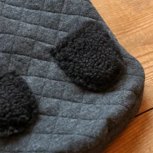 Closeup detail of dark grey quilted pet winter coat with cute fuzzy black plush ears.