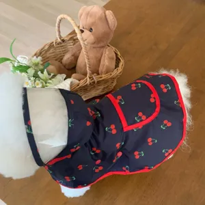 Vue détaillée d'un chien portant un imperméable pour animaux bleu marine à motif cerise.