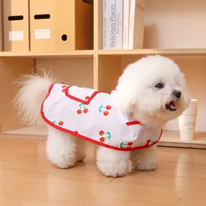 Détail en gros plan d'un joli imperméable pour chien avec bordure rouge et motif de cerises.