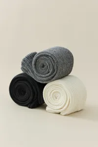 Close-up detail of ribbed knit knee-high slouch socks in black, grey, and cream colors.