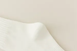 Close-up detail of knitted cream women knee high socks, soft fabric texture shot.